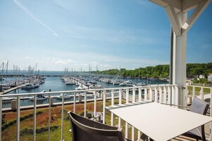 Una terrazza con vista su un porto turistico, arredi da esterno e una ringhiera bianca.
