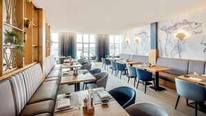 A restaurant with a long counter, booths, and a mural of fish on the wall. - Lindner Hotel Boltenhagen (Boltenhagen)