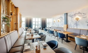 A restaurant with a long counter, booths, and a mural of fish on the wall. - Lindner Hotel Boltenhagen (Boltenhagen)
