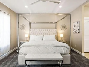 A four-poster bed with a tufted headboard, bedside tables with lamps, and a bench at the foot of the bed. - Southern Utah 9BR / 26-Guest Luxury Estate (Hurricane)