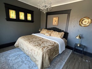 Un dormitorio con cama, una araña, un cuadro en la pared y una lámpara.