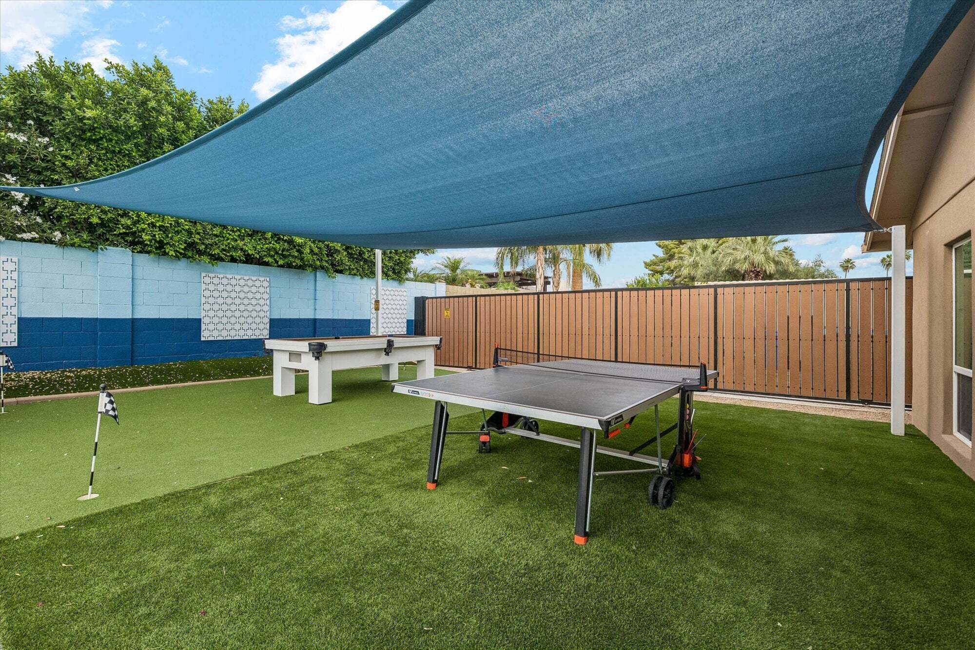 Un jardin avec une table de ping-pong, une table de billard et un petit espace aménagé en jardin.
