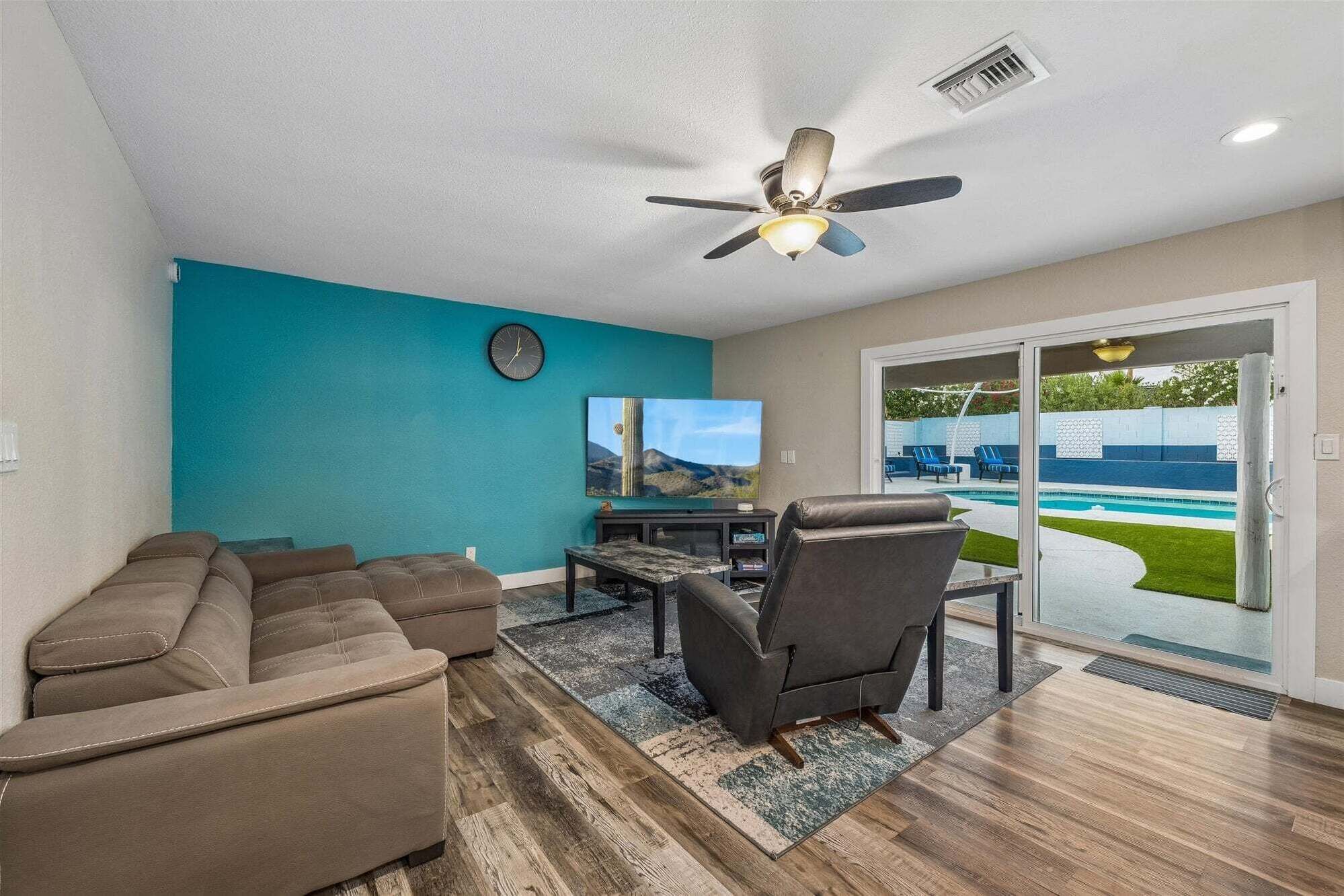 Ein Wohnzimmer mit Sofa, Sesseln, Fernseher und Deckenventilator.