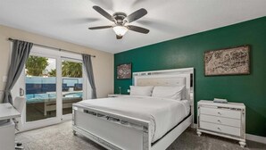 Ein Schlafzimmer mit einem Bett, einem Schreibtisch, einem Stuhl, einem Nachttisch und einem Deckenventilator.