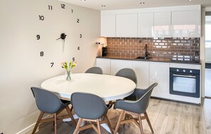 A modern kitchen with white cabinets, a brick backsplash, and a round dining table with chairs. - Awesome apartment in Faaborg with sauna (Faaborg)