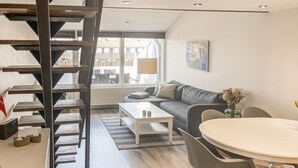 Een moderne woonkamer met een trap, een bank, een salontafel en een eethoek.