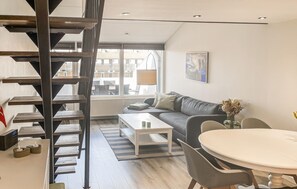 A modern living room with a staircase, a sofa, a coffee table, and a dining area. - Awesome apartment in Faaborg with sauna (Faaborg)