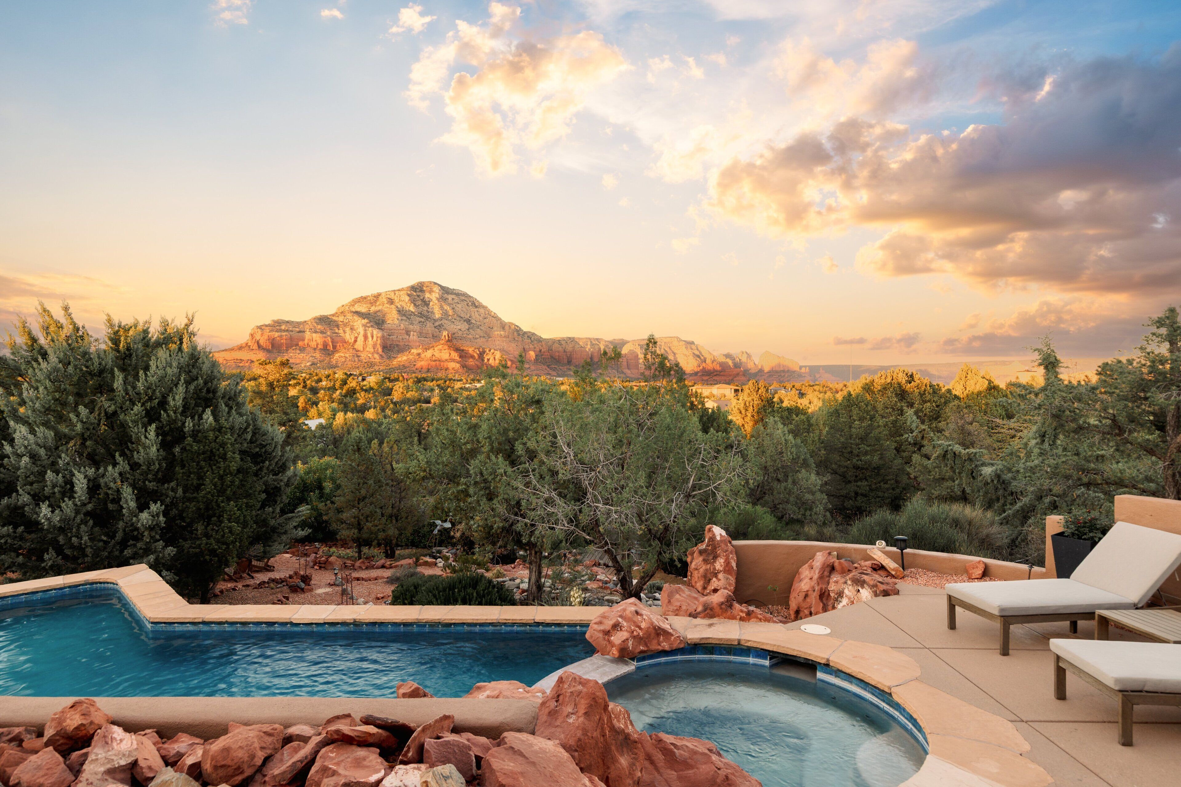 A swimming pool with a view of a mountain, surrounded by trees and rocks.