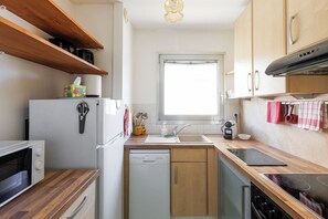 Cocina compacta con refrigerador, microondas, lavavajillas y estufa.