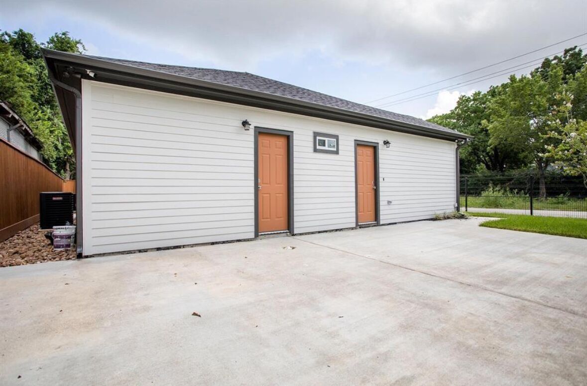 Un bâtiment d’un seul étage, doté d’une porte de garage, de deux fenêtres et d’une petite structure adjacente.