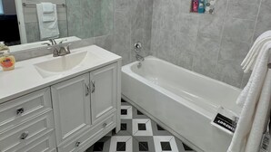 Ein modernes Badezimmer mit großem Spiegel, zwei Waschbecken, einer Badewanne und einer Dusche.