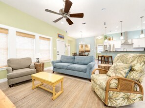A living room with a ceiling fan, a sofa, a coffee table, and a patterned armchair. - Coastal Cotter | Sunset Patios + Pet Friendly! (Port Aransas)