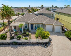 A single-story house with a covered patio, a garage, and a fenced yard. - Coastal Cotter | Sunset Patios + Pet Friendly! (Port Aransas)