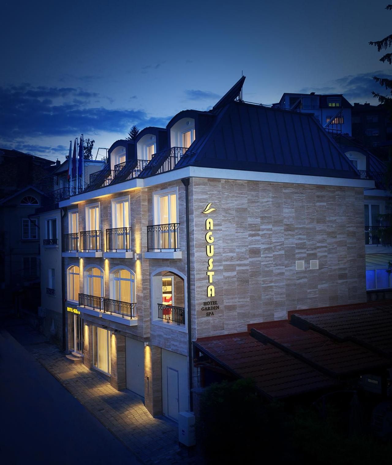Un hotel con fachada de piedra, varios balcones y un letrero que indica que es un spa jardín.
