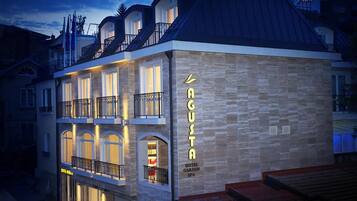 Un hotel con fachada de piedra, varios balcones y un letrero que indica que es un spa jardín.