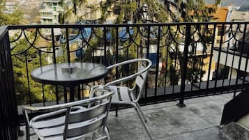 Un balcón con una mesa redonda y dos sillas, con vistas a una zona residencial con casas y árboles.