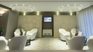 A modern waiting area with two white chairs, a television screen, and a decorative ceiling. - Agusta Spa Hotel (Veliko Tarnovo)
