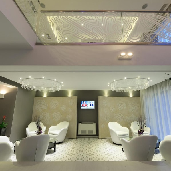 A modern waiting area with two white chairs, a television screen, and a decorative ceiling. - Agusta Spa Hotel (Veliko Tarnovo)