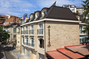 A multi-story hotel with balconies, a stone facade, and a sign indicating it is a hotel and spa. - Agusta Spa Hotel (Veliko Tarnovo)