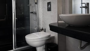 A modern bathroom with a glass shower enclosure, a white toilet, and a large vessel sink. - Agusta Spa Hotel (Veliko Tarnovo)