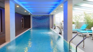 An indoor swimming pool with a blue mosaic wall, a water feature, and a seating area with lounge chairs. - Agusta Spa Hotel (Veliko Tarnovo)