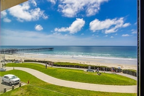 A coastal view with a pier, beach, and a parking area with a white car. - Sparkling sunset views of PACIFIC BEACH!! (San Diego)