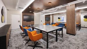 Uma sala de conferências com uma mesa comprida, várias cadeiras e uma tela grande.
