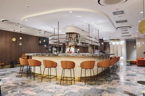 A bar area with a circular bar, multiple stools, and a bartender. - The Hotel Katowice (Katowice)