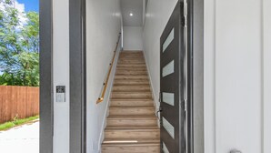 A staircase with wooden steps leading to a dark door with glass panels. - Modern Fort Worth Stay w/ EV Charger Near TCU, ATT Stadium & Downtown (Fort Worth)