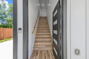 Eine Treppe mit Holzstufen, die zu einer dunklen Tür mit Glasscheiben führt.