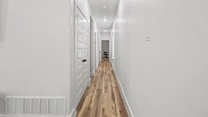 A hallway with white walls, wooden flooring, and white doors. - Modern Fort Worth Stay w/ EV Charger Near TCU, ATT Stadium & Downtown (Fort Worth)