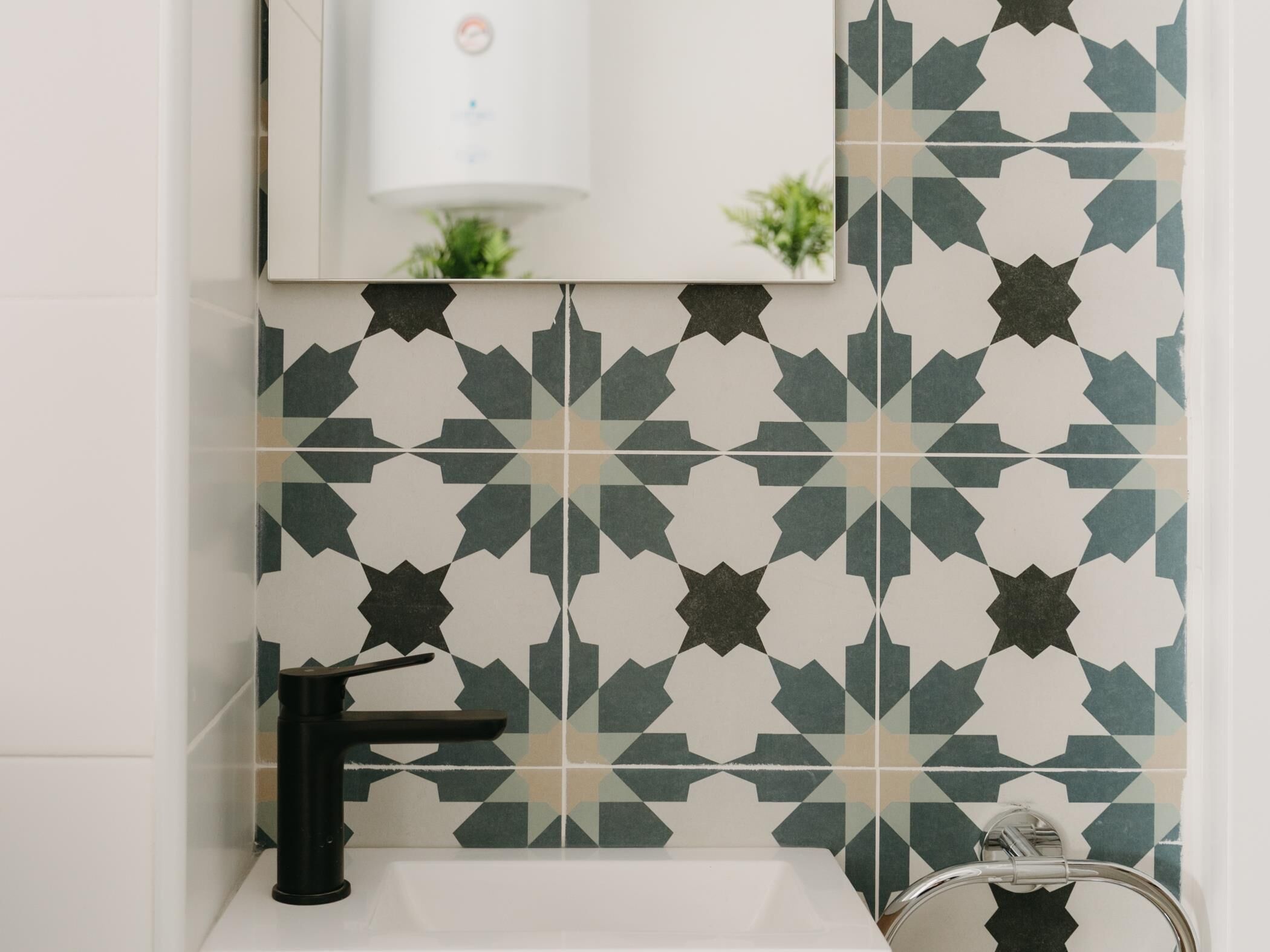 A bathroom with a black faucet, a white sink, and a mirror above.
