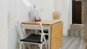 Een klein eethoekje met een witte tafel, één stoel en een waterdispenser.