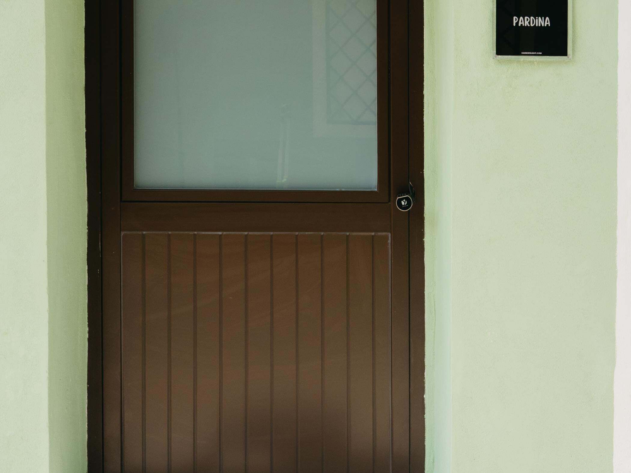 Uma porta marrom com painel de vidro jateado e uma pequena placa em cima.