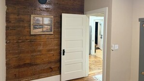 Un mur en bois avec une porte, un tableau encadré et un interrupteur.