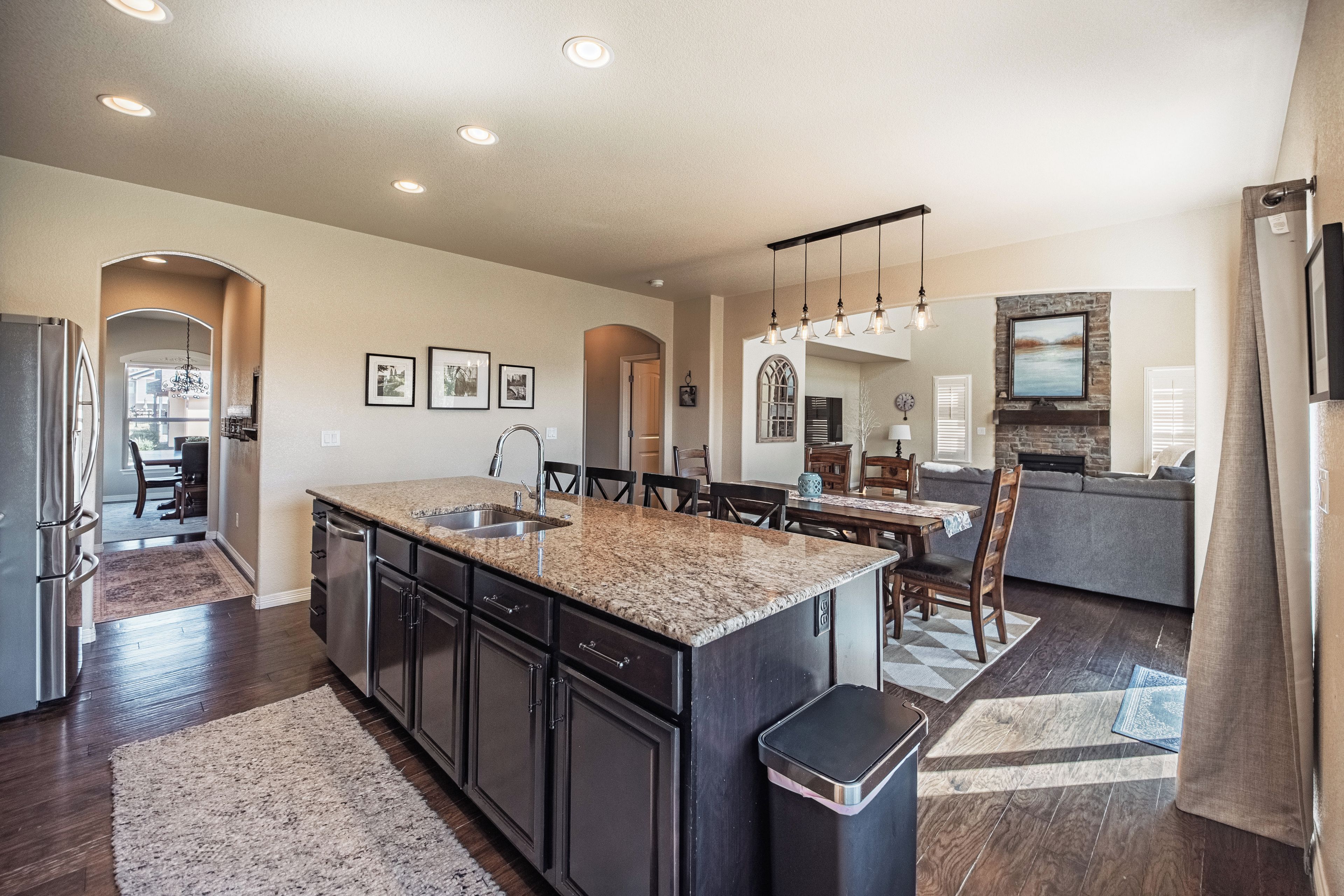 A spacious kitchen with a granite countertop, stainless steel appliances, and a dining area with a table and chairs.