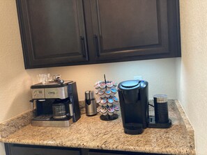 A kitchen counter with a coffee maker, a Keurig coffee maker, a coffee pod holder, and a coffee grinder. - Mountain Views, Air Force Academy, Hot Tub, Pet Friendly, Hiking, Trails, Dining (Colorado Springs)
