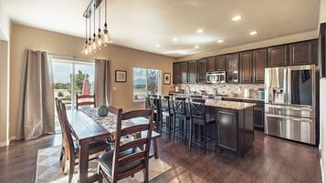 A modern kitchen with dark wood cabinets, stainless steel appliances, and a dining area with a wooden table and chairs.