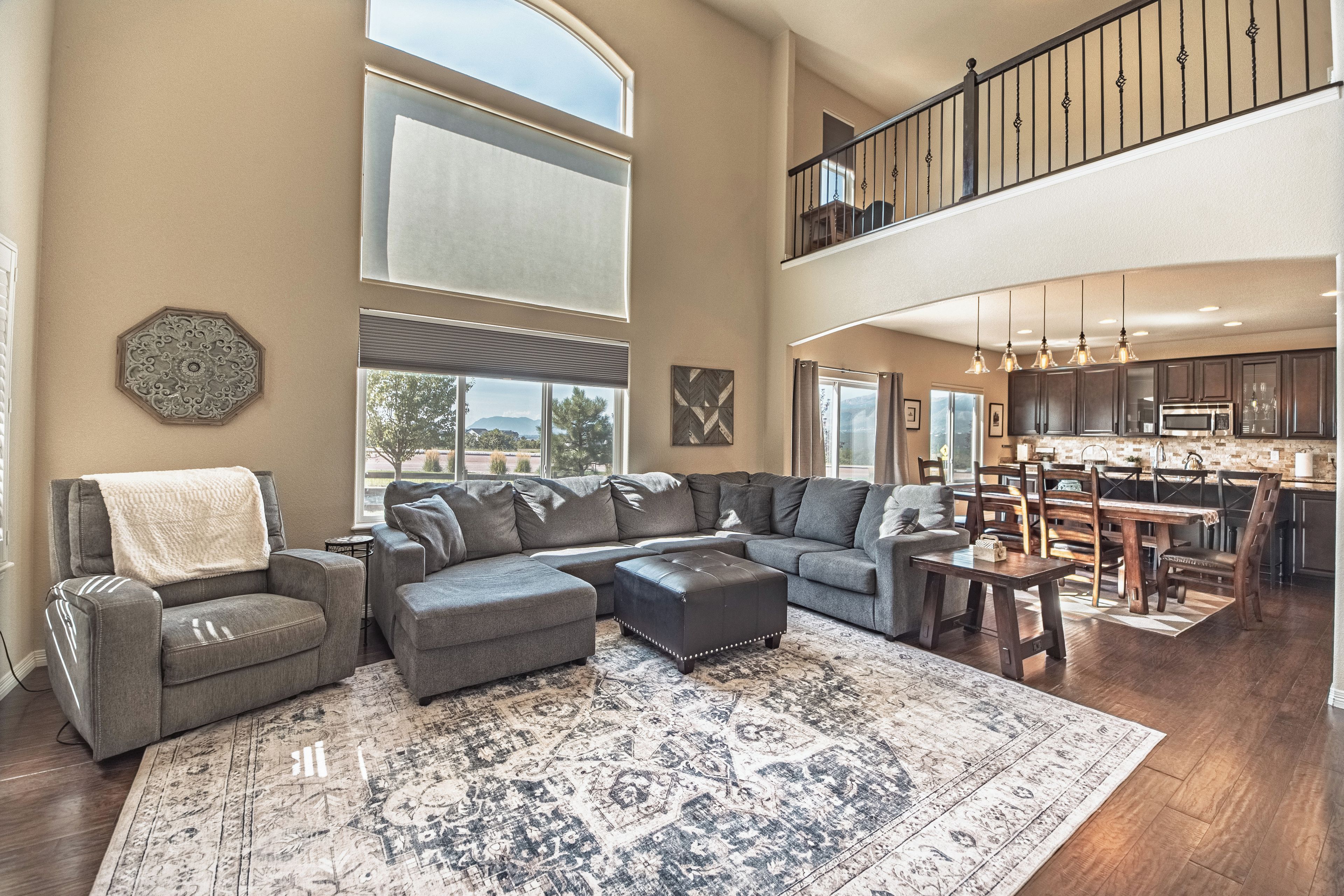 A spacious living area with a sectional sofa, ottoman, and a large rug.