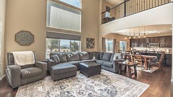A spacious living area with a sectional sofa, ottoman, and a large rug.