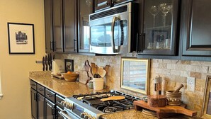 Una cocina con armarios oscuros, electrodomésticos de acero inoxidable, encimeras de granito y salpicadero.