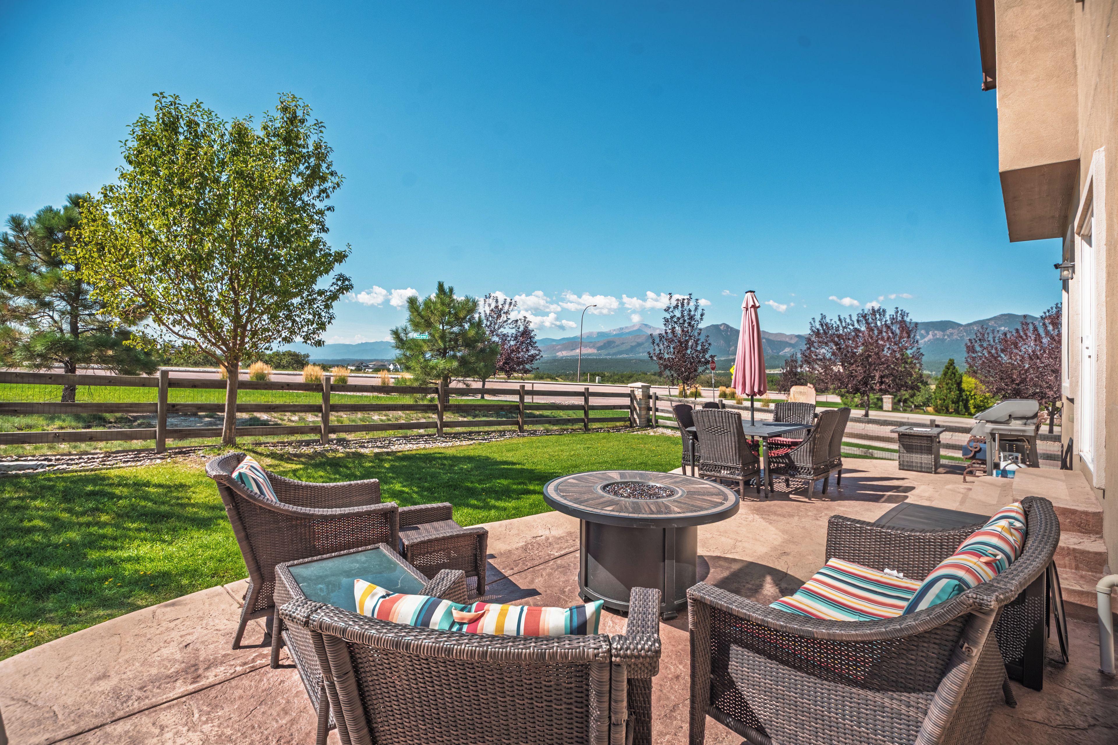 An outdoor patio with wicker furniture, a fire pit, and a view of mountains.