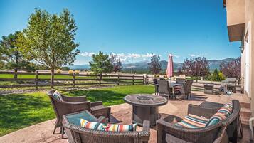 An outdoor patio with wicker furniture, a fire pit, and a view of mountains.