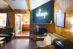 A cozy living area with leather sofas, a fireplace, and a neon sign. - 5 Bedroom Mid Term Rental in Bryan "The WHOOP" (Bryan)