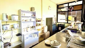 Una cocina con electrodomésticos de acero inoxidable, estantes con utensilios de cocina y una ventana con vistas.