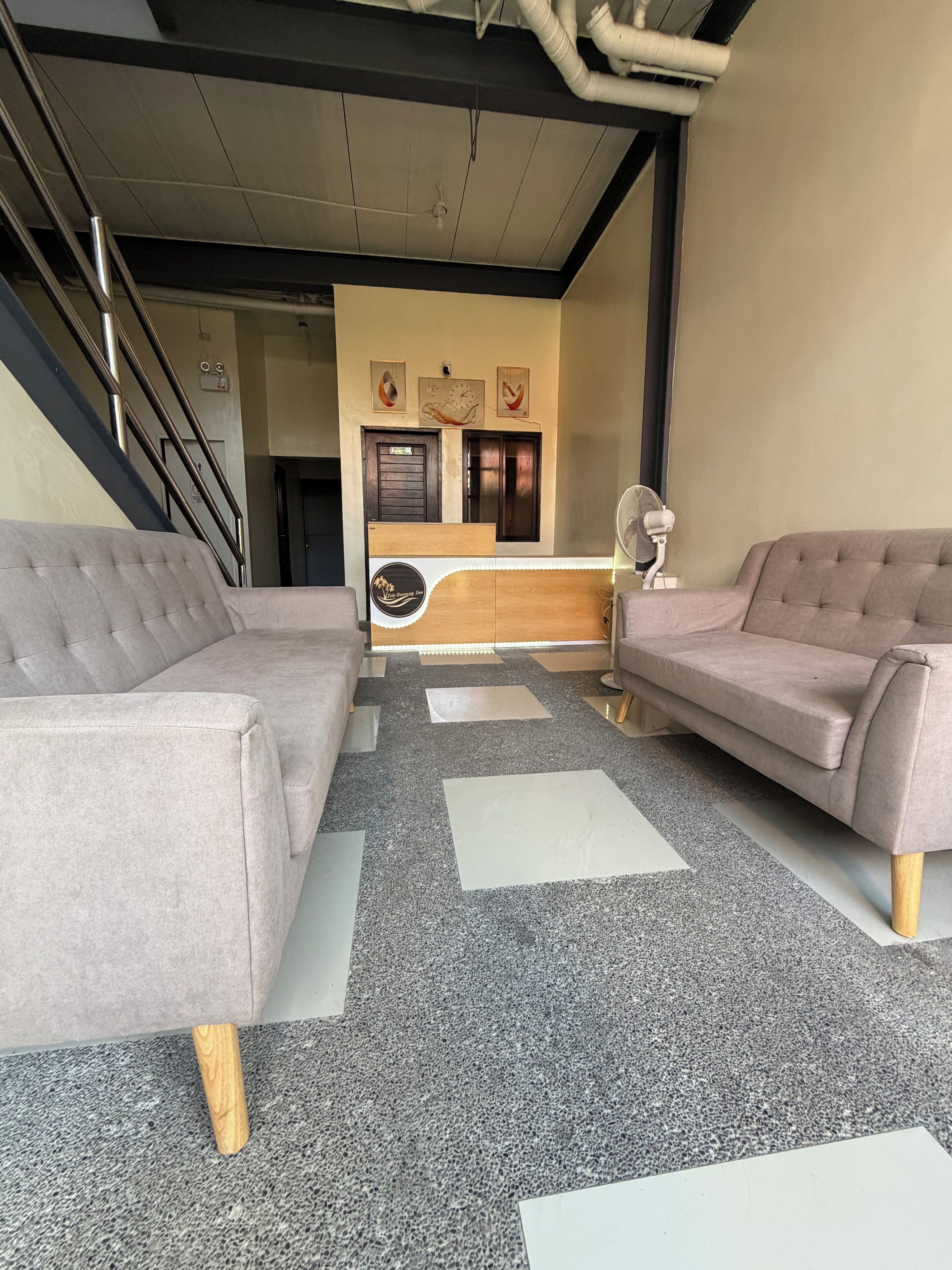Un vestíbulo moderno con dos sofás, un mostrador de recepción y una escalera.