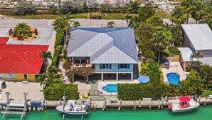 Una casa con techo azul, piscina y muelle con barcos.
