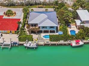 A house with a blue roof, a swimming pool, and a dock with boats. - Waterfront Marathon FL Home w/ Pool, 75' Dock, Near Sombrero Beach, Pet Friendly (Marathon)