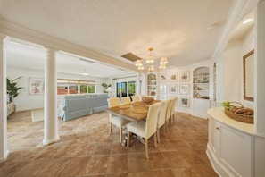 A spacious dining area with a wooden table, chairs, and a chandelier. - Waterfront Marathon FL Home w/ Pool, 75' Dock, Near Sombrero Beach, Pet Friendly (Marathon)