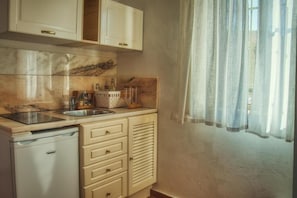 Eine kompakte Küche mit Spüle, Geschirrspüler und einem Schrank mit Fenster darüber.